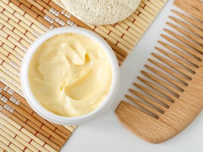 Yellow facial mask (banana face cream, shea butter hair mask, body butter) in the small white container. Natural skin and hair concept. Top view, copy space.