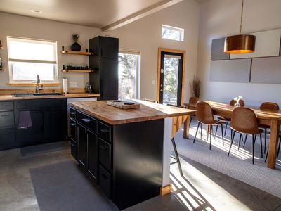 wide shot of minimalist modern open kitchen and dining room with sunlight galore