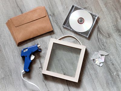 a flat lay shot of cd's and a picture frame and hot glue gun for upcycling