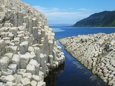 White basalt columns submerged in sea at Cape Stolbchatiy, Russia