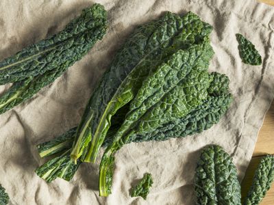 Raw kale leaves on a beige cloth on wooden surface