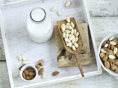 Glass bottle of almond milk surrounded by whole almonds