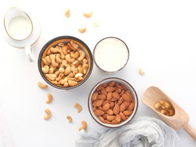 Bowls of cashews, almonds with milk in glasses overhead shot