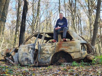 Alastair Humphreys sits atop an old car