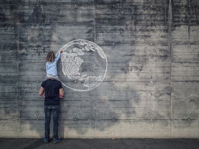 Austria, Salzburg, Father with daughter on his shoulders, the daughter draws with chalk the earth on a concrete wall