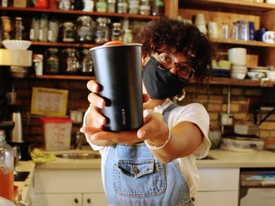 barista holds out reusable Muuse coffee cup