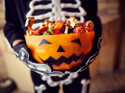 Boy in skeleton costume holding bowl full of candies