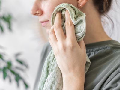 woman uses green washcloth and homemade diy makeup remover to clean face