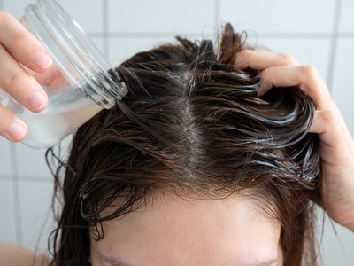 overhead shot of person in shower washing hair with diy shampoo in glass jar