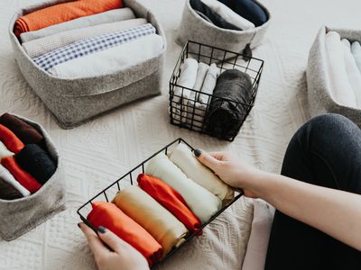 Folding clothes and organizing stuff in boxes and baskets. Concept of tidiness, minimalist lifestyle and japanese t-shirt folding system.