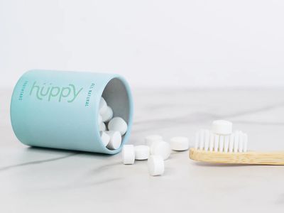 Can of toothpaste tables and a bamboo toothbrush