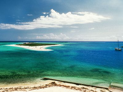 aerial view of bright white sand surrounded by shallow, blue and turquoise waters of one of the small islands of Dry Tortugas with two boats just offshore