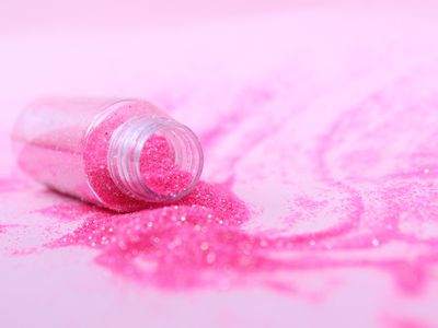 Close Up Of Scattered Pink Glitter With Bottle On Table - stock photo