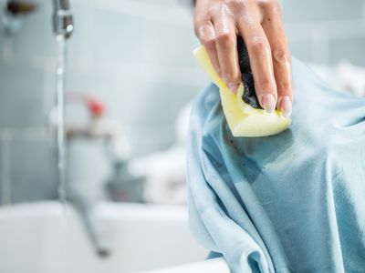 Woman cleaning a stained shirt with a sponge