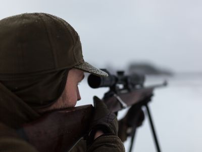 Deer hunter aiming with a gun