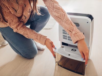 Person removing tank from dehumidifier on the floor