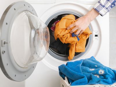 persons hand put dirty clothes in the washing machine