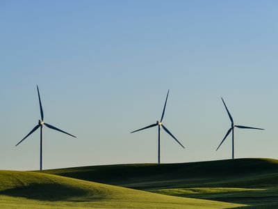 Three wind turbines on a landscape of rolling hills and blue sky.