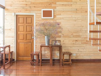 Reclaimed wooden wall with a wooden door, table sets and flowers in zinc vase in bright sunlight.