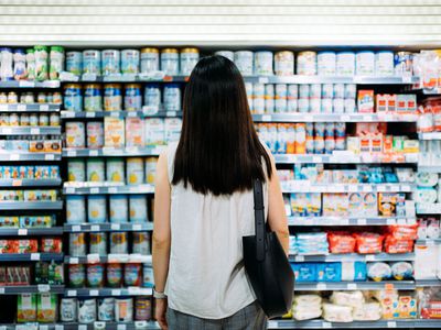 woman stands in front of overflowing food display consumer overload