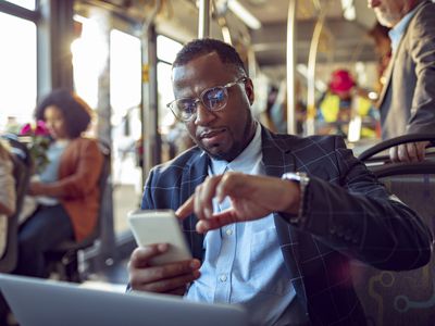 businessman works on smartphone while commuting to work on a city bus