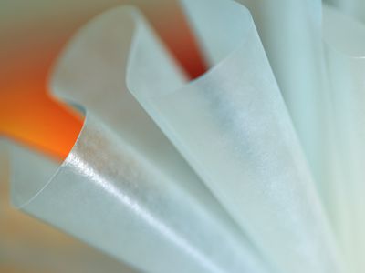 Abstract image of fluted wax paper creating grooves and curves against bright orange background