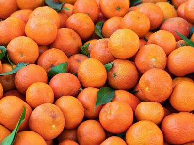 pile of fresh oranges with stem and leaves still attached