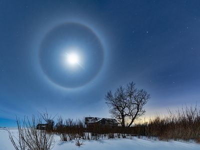 A lunar halo shines above a farm house in winter.