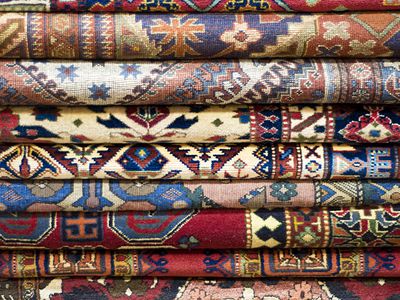 Patterned vintage rugs in a folded stack.