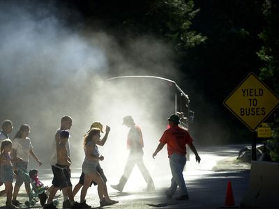 Pedestrians walk through a cloud of dust and diesel exhaust from a transit bus near Yosemite Village, June 16, 2000 in Yosemite National Park, California. 