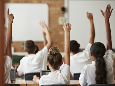 students in school all raise hands to ask a question