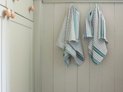 Two dish towels hanging on hooks next to a cabinet