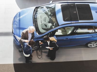 People inspecting a used electric vehicle at a dealer.