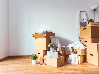 Cardboard moving boxes piled on a wood floor.