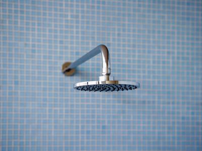 minimalist blue tiled shower with modern flat shiny chrome shower head