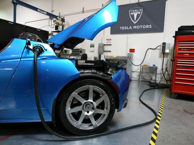 A blue Tesla Roadster car recharging.