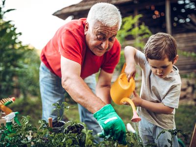 grandfather and grandson watering plants in garden