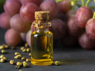 Grape seed oil in a glass jar and fresh grapes