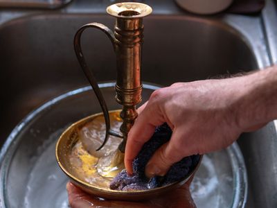 hands clean brass candlestick in sink