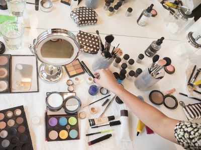 Hispanic woman selecting makeup from table