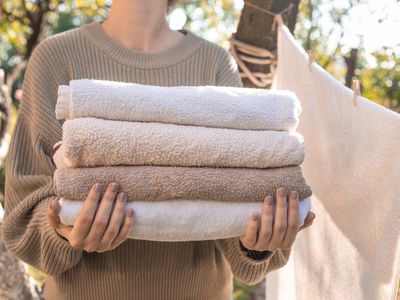 woman holds stack of towels outside