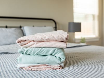 neatly folded bed sheets sit on top of made up bed in bedroom