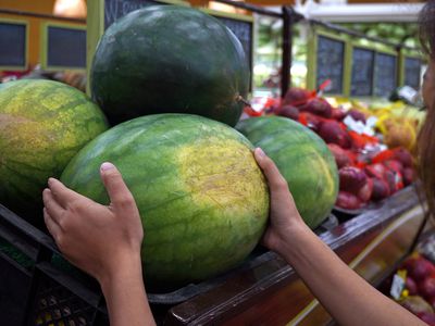 hands reach out for watermelon at store