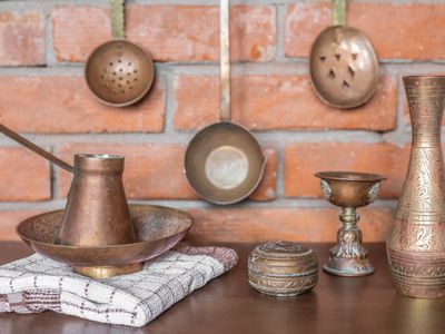 shot of copper and brass cooking utensils against brick