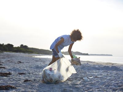 Person collecting trash from beach and putting it in bag