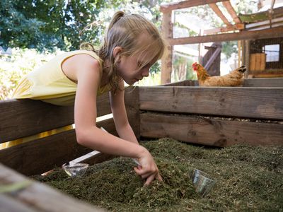 little girl buries compostable plastic cup in compost bin