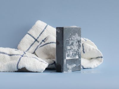 gray block of bar soap with foam next to striped towel