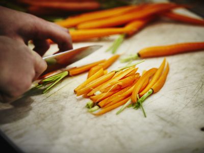 Man slicing carrots on cutting board in kitchen