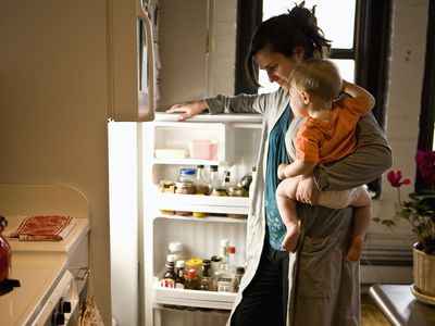 mother holding son looks in fridge for ingredients