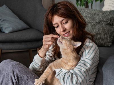 woman hugs kitty while booping on nose